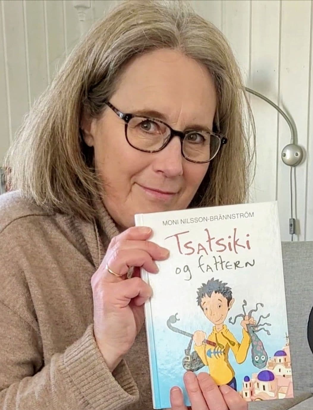 Anne Karin (56) med en av favorittbøkene hennes, "Tsatsiki og fattern" av Moni Nilsson-Brännström.